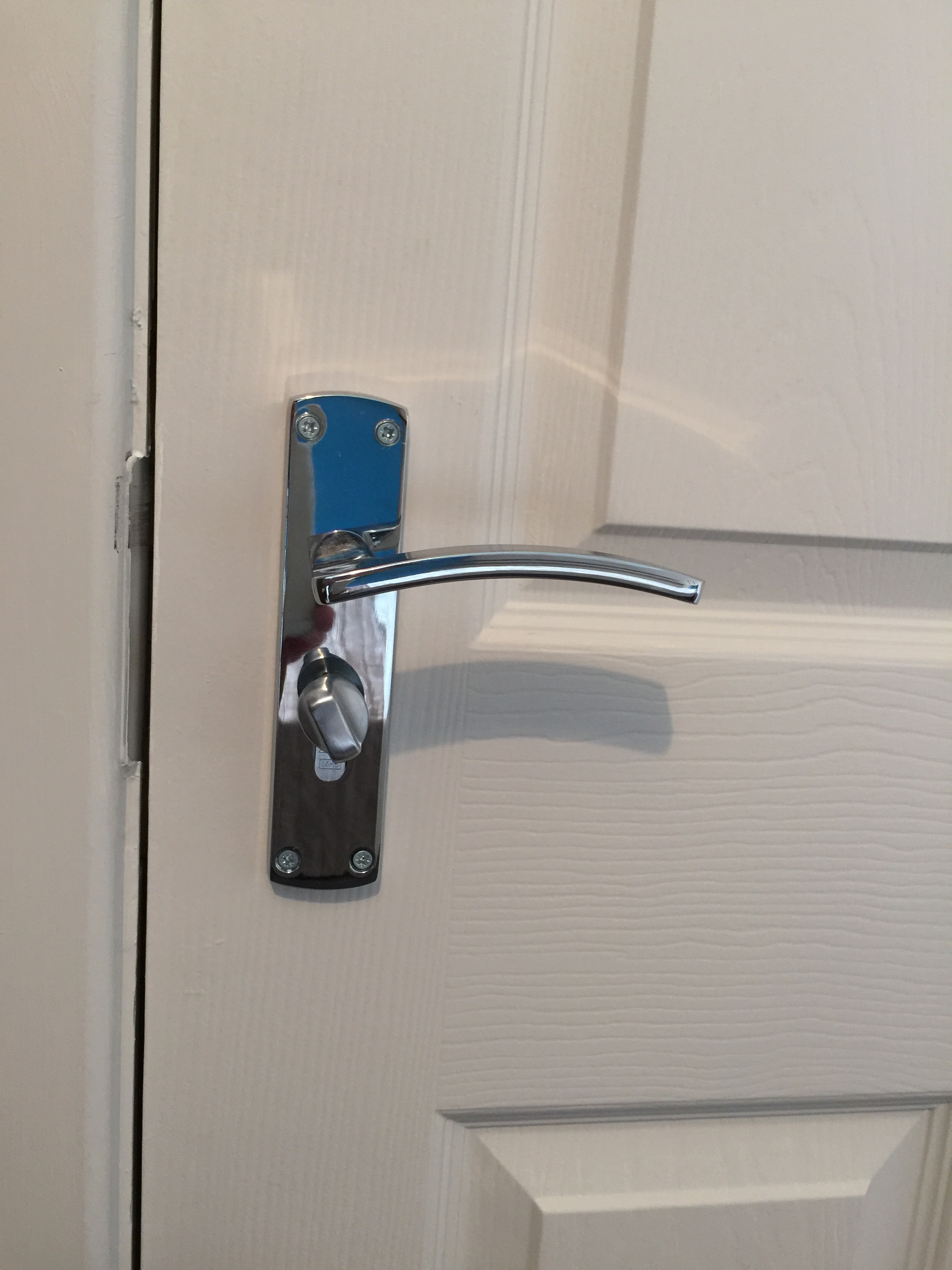 Close up photo of a door handle and a thumb-turn lock. Thumb-turn locks are an essential part of fire safety and HMO fire regulations.
