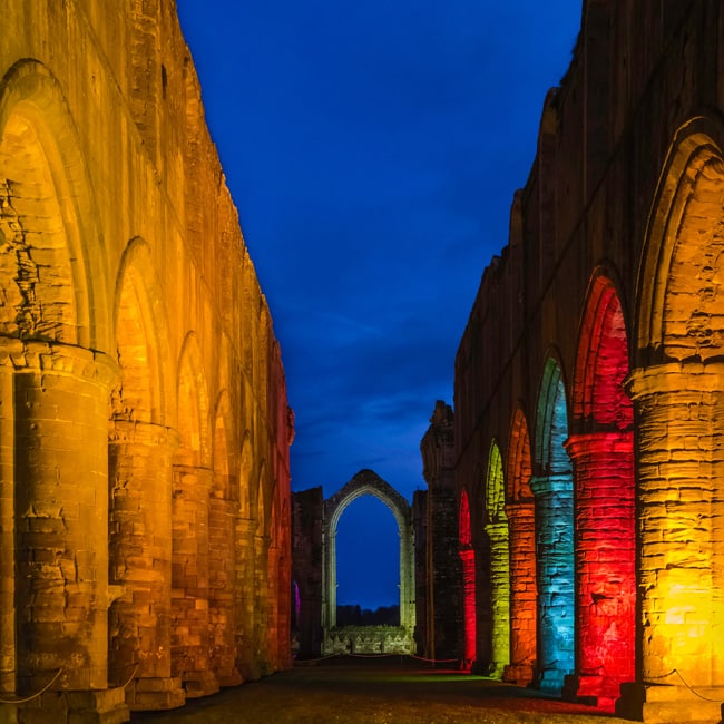 Arched buttresses lit in colour at Fountains Abbey, near Ripon in North Yorkshire