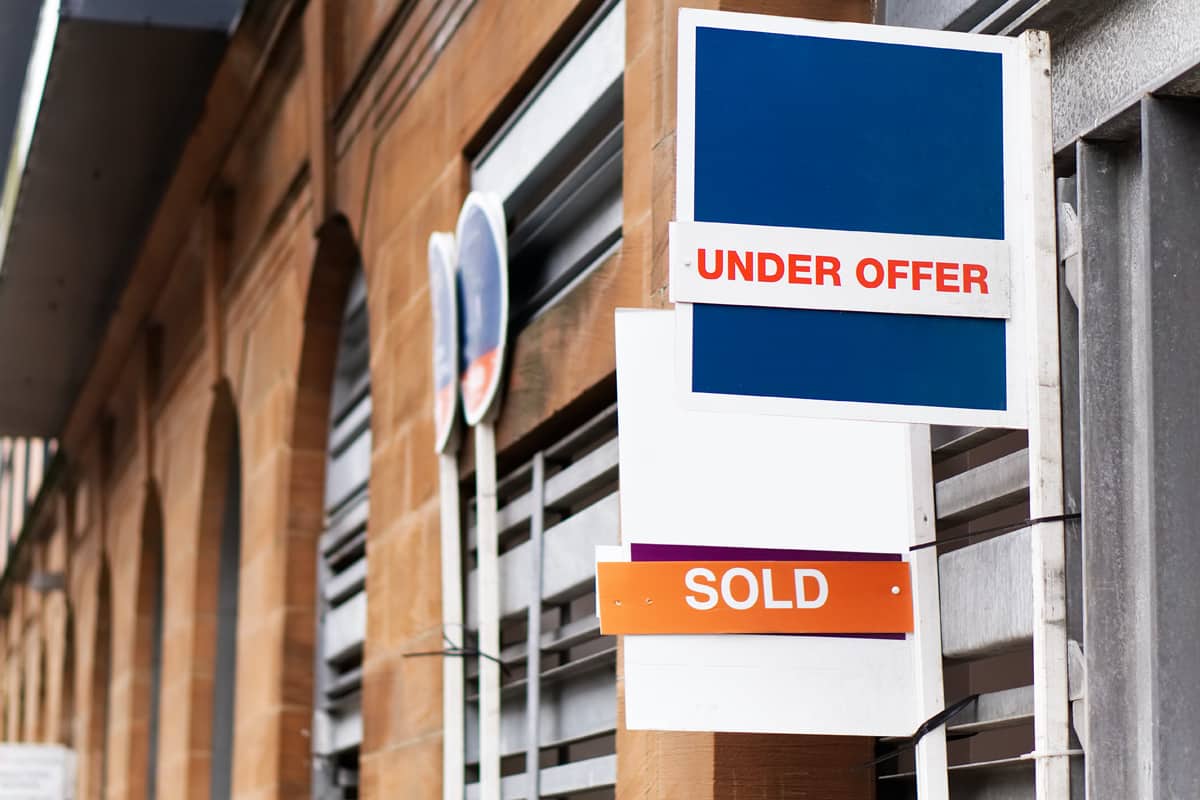 Estate Agent Signs, UK Two estate agent signs on a building, 1 showing 'Under Offer' and the other showing 'Sold'