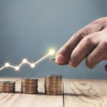 Man stacking coins against a graph that represents profit.