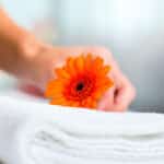 Maid doing room service in hotel, she is making up a bed and is putting a flower on the bed clothes.