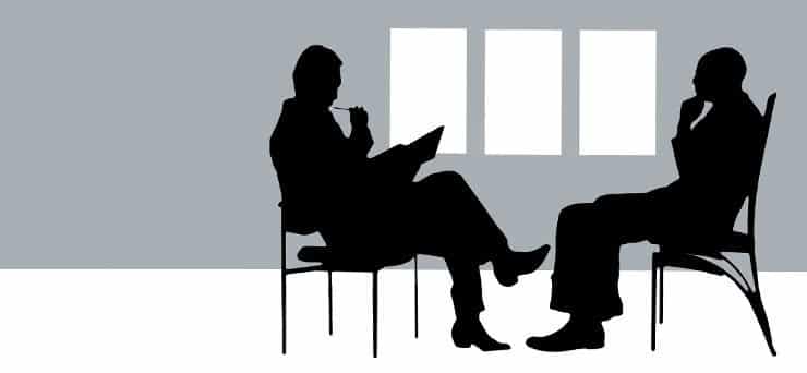 A graphic. A black and white vector image of two people sitting across from each other in a meeting.