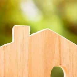 A wooden model of a house against a blurred, green background.