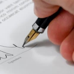 Close up photograph of a man signing a contract.