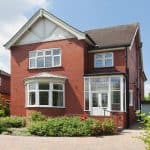 A photograph of a traditional red-brick English detached house.