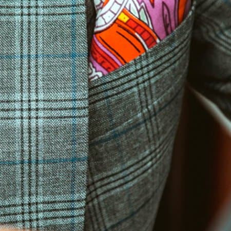 A close up photograph of a handkerchief sticking out of the top pocket of a tailored suit.