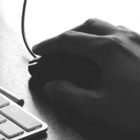 A black and white image of a hand on a computer mouse.