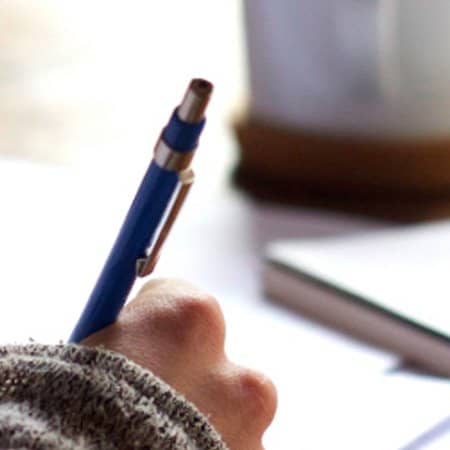 A close up shot of someone filling in some paper work.