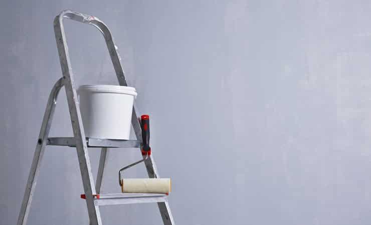 A photo of a paint pot and a roller on a ladder