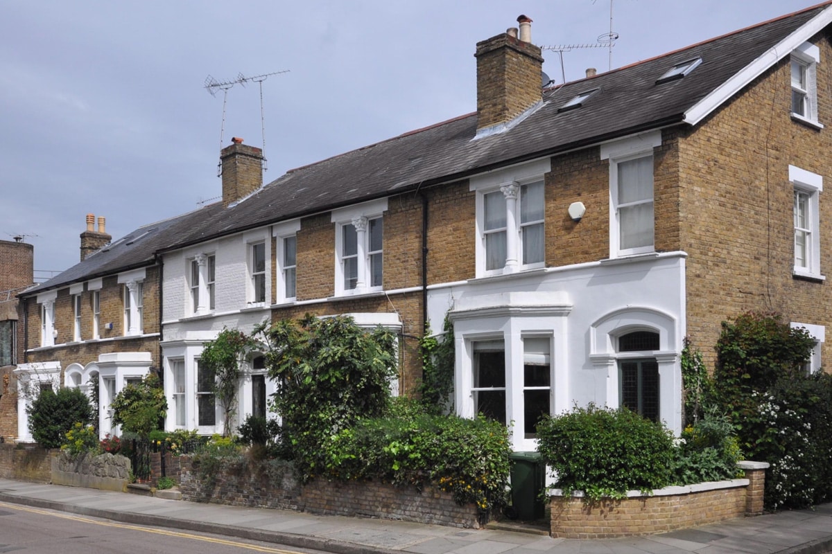 A terrace of UK townhouses, built in the 19th century. The fronts of the houses are a a mixture of white paint and exposed brick.