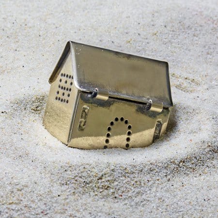 Picture of a model house sinking in some sand.