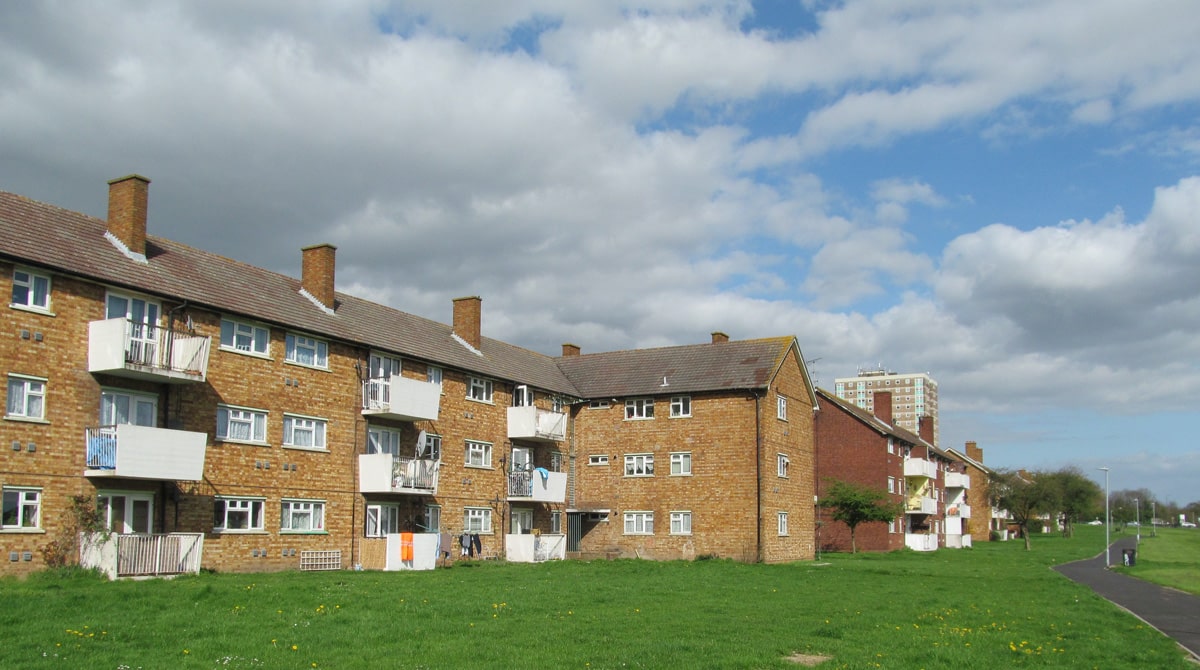 Three story 1950s council flats in white and exposed brick on the Marks Gate Estate in Dagenham