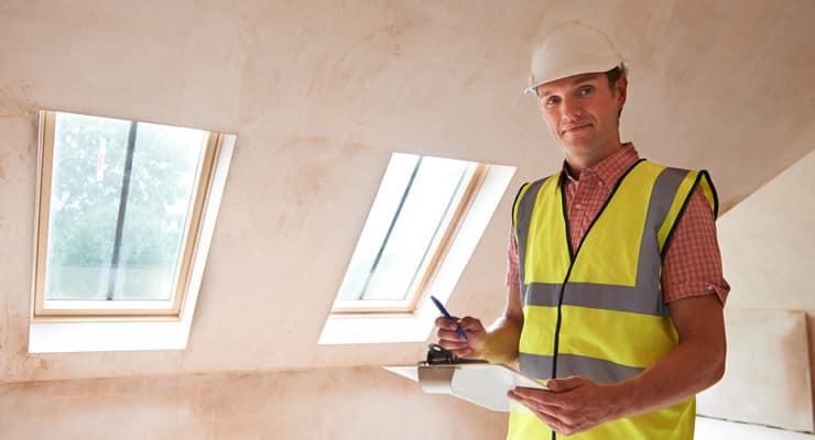 A building inspector wearing a high-vis vest and hard hat inspects a new-build property