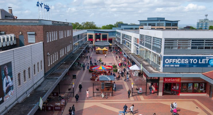 A high-up view of shoppers in Wythenshawe Forum, an outdoor shopping centre in South Manchester