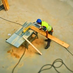 A bird's eye view of a construction worker cutting wood on a construction site.