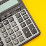 A close-up photograph of a calculator, sitting on a yellow surface.