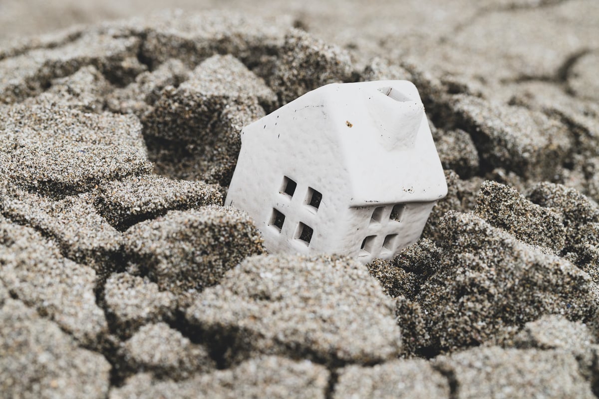 A model house sinks into some broken sand. Image represents subsidence