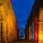 Arched buttresses in colourful lights. Photograph taken at Fountains Abbey, near Ripon in North Yorkshire.