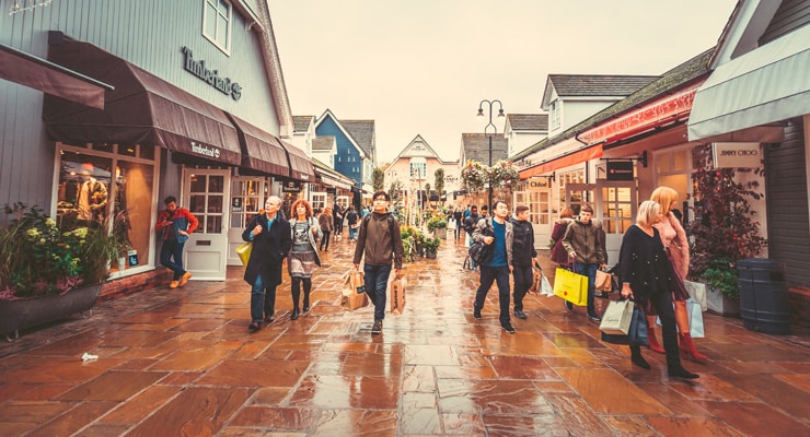 A busy shopping street in the rain. Photograph of Bicester Village Outlet