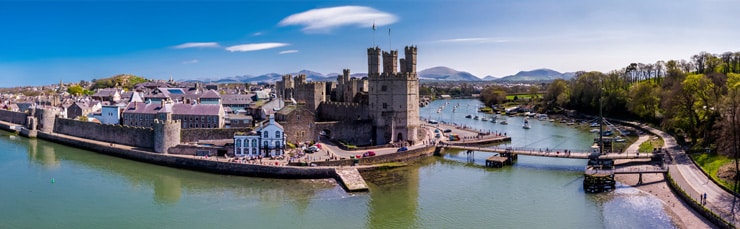 Aerial image of the skyline of Caernarfon in North Wales. Photograph shows Caernarfon castle, the harbour and the mountains of Snowdonia