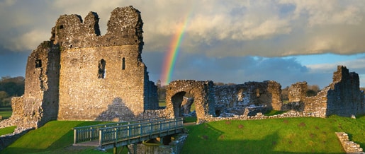 Photo of Ogmore Castle with a rainbow in the background