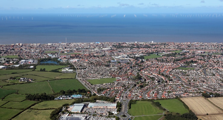 Aerial photograph of Rhyl, North Wales with the ocean and coastline visible and an off-shore wind farm in the distance