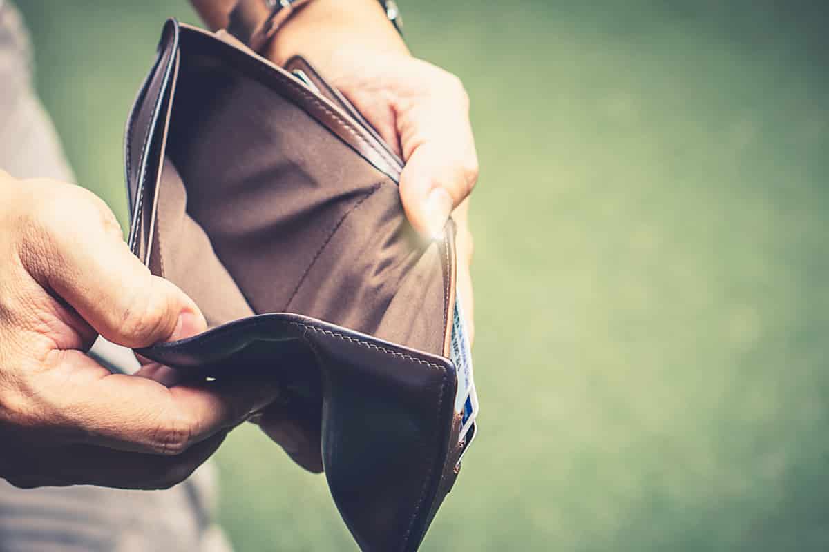 A man opens his wallet to reveal that it is empty. Represents no money