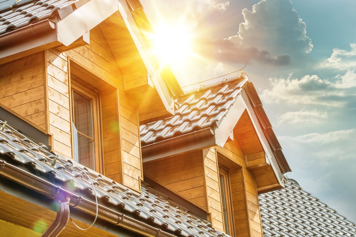 Sun breaks through clouds over a house roof and attic window. Picture represents a release of equity.