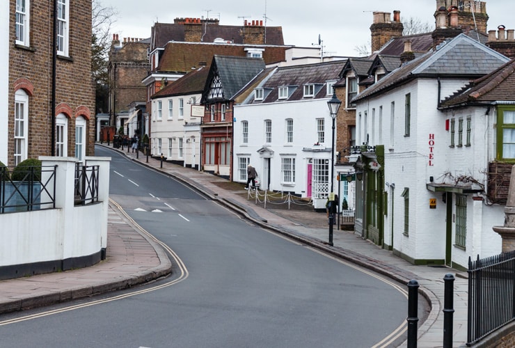 Traditional pubs, restaurants and shops on a sloping high street. Photograph taken in Harrow on the Hill in Harrow, West London.