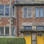 A large semi-detached house with a yellow door and lead lined old-world windows. Image is of an HMO (a House of Multiple Occupation).
