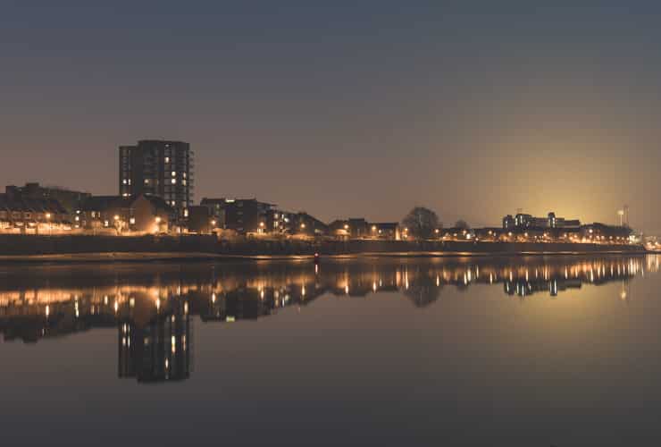 The lights of Fulham are reflected by the River Thames at night.