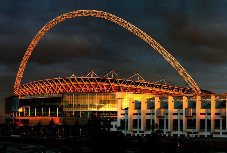 Wembley Stadium in Brent. Photograph taken at night with the stadium illuminated by upward facing lights.