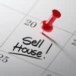 A calendar with a pin in a particular day with the words, sell house written in that day's square.