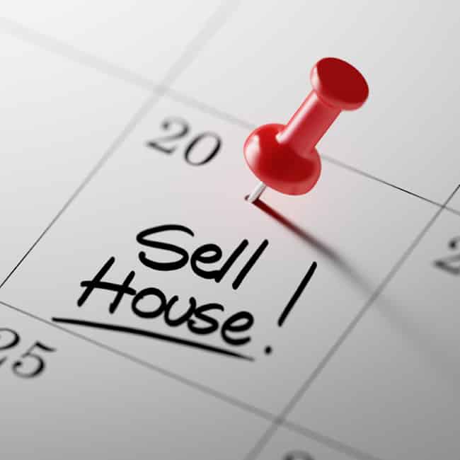 A calendar with a pin in a particular day with the words, sell house written in that day's square.