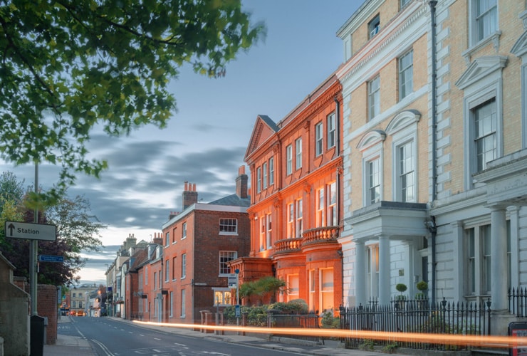 Southgate Street in central Winchester on a warm summer's evening at dusk. Cars are passing and captured as light trails.