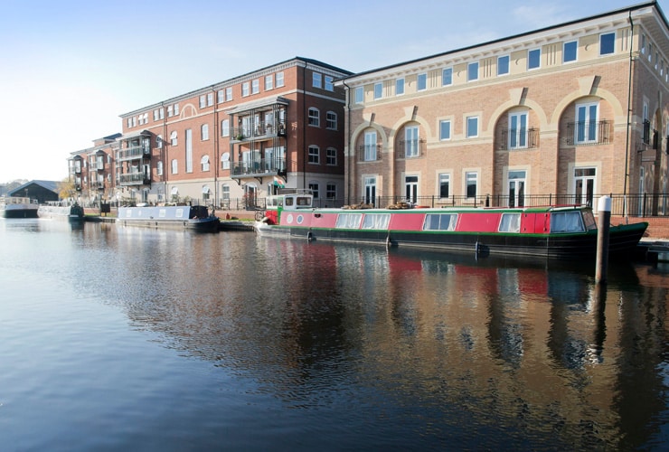 Narrow boats on the waterfront with industrial buildings alongside. Photograph taken at the canal basin, Diglis, in Worcester.