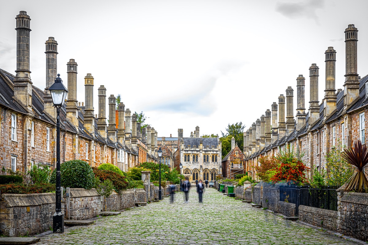 A view down the historic Vicars' Close in Wells. Old stone buildings line a cobbled road.