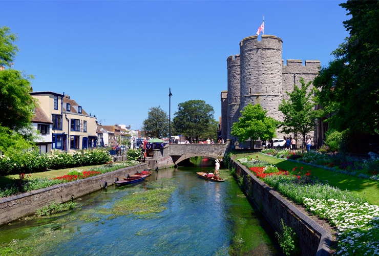 People punting along the Great Stour with Wesgate Towers in the background.