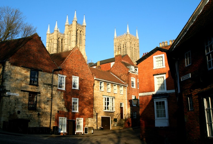 Medieval Streets of the City of Lincoln, Lincolnshire, UK, with the towers of the Cathedral above the ancient buildings, near sunset.