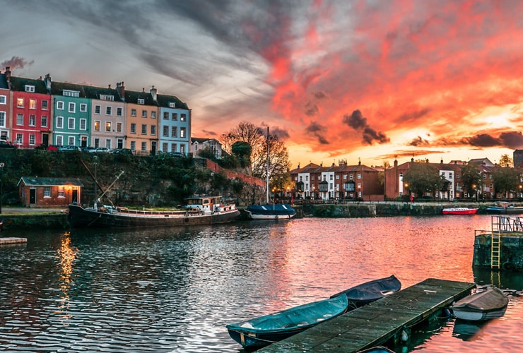 Bristol harbour at sunset with brightly coloured residential buildings in the background.