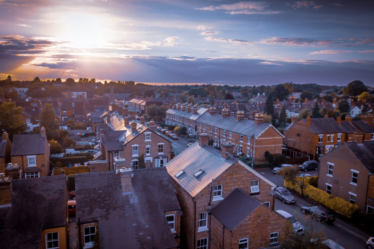 Sunset over traditional British houses with countryside in the background.