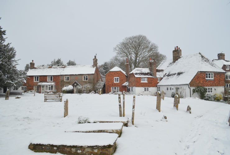 A photograph of hellingly church grounds and cottages under deep snow. The grounds are near Hailsham in East Sussex.