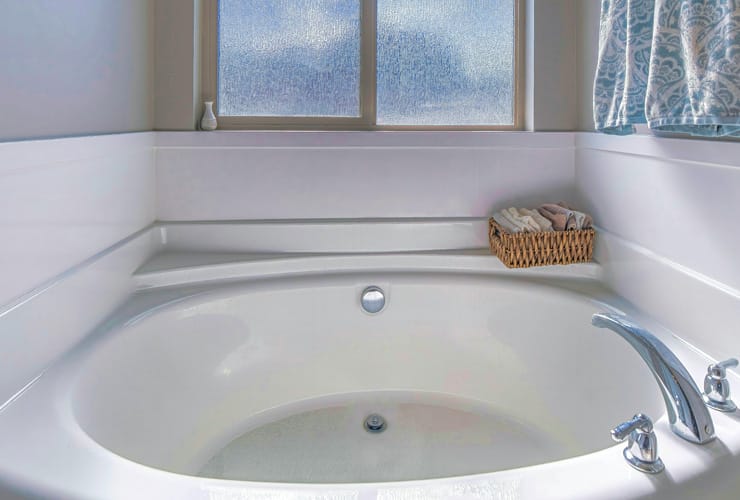 A Pano Round built in bathtub with stainless steel faucet inside residential bathroom. A circular bath shape.