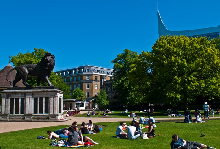 Groups of young people sat in a park on a summer day. Photograph taken in Forbury Gardens in Reading, UK.