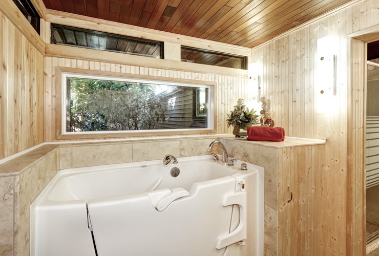 A walk-in bath in a wood-panelled bathroom.