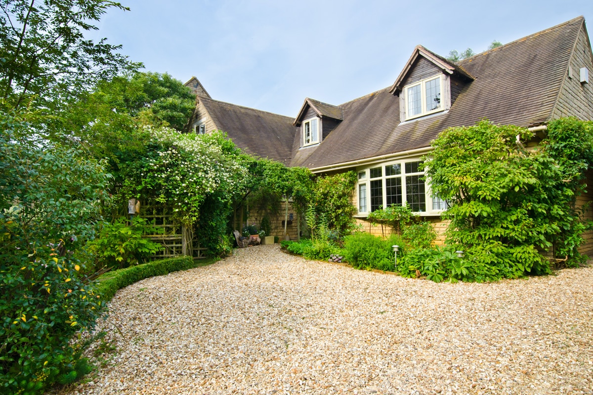 An English cottage with a gravel driveway.