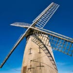 Bidston Windmill, on Bidston Hill in Birkenhead, Wirral, UK on a sunny day with a clear, blue sky. A sail casts a shadow across the structure of the mill which was built around 1800.