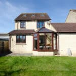 Rear garden of a four bedroom detached house with glass conservatory and link detached garage.