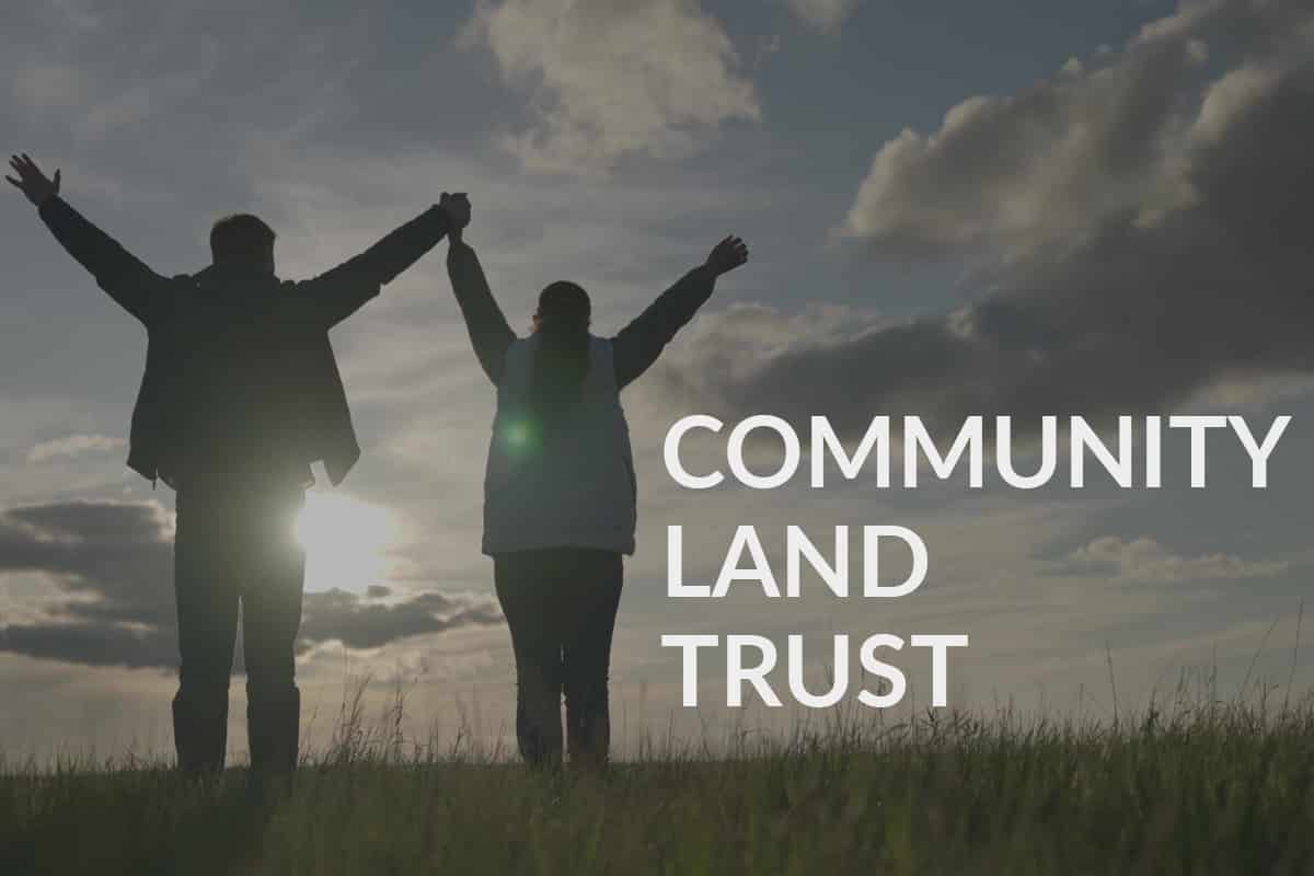 A man and a woman hold hands with their arms lifted up against a sunset. Text says, 'community land trust'.