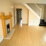 An empty lounge with a fireplace and staircase in the corner.